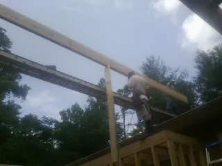 Carpenter setting a ridge beam over a new addition frame — Ice Dam Removal by Roofing Brothers in Weymouth