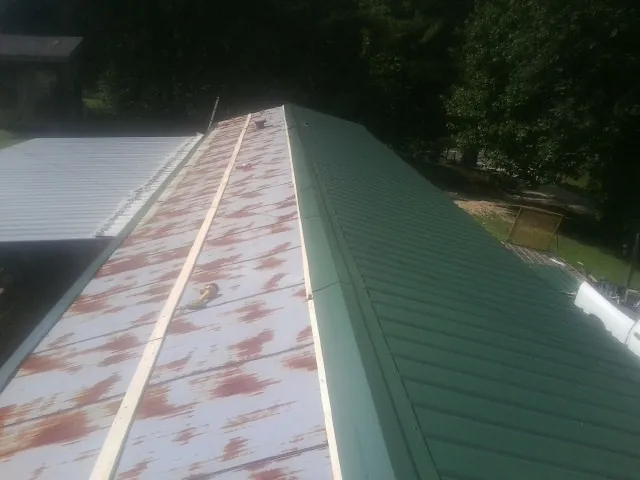Old rusted panels beside newly installed green metal roofing — Wind Damage Roof Repair by Roofing Brothers in Weymouth