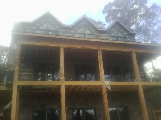 Dormers and porch framing on a large log home under construction — Roof Coating work by our crew in Weymouth
