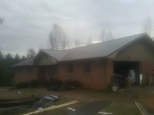 Gray metal roof on a stucco house with an attached garage in Weymouth