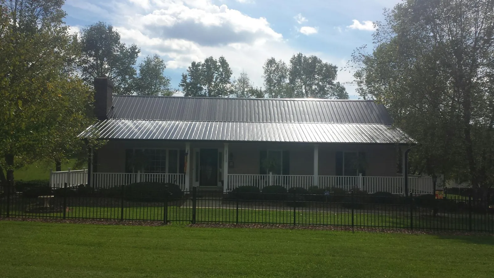 Gray metal roof on a brick ranch with a full width front porch — Gutter Guard Installation work by our crew in Weymouth