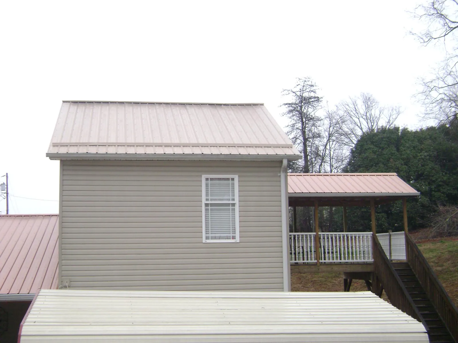 Tan metal roofs on a two story addition and attached porch, from a Roof Replacement job in Weymouth