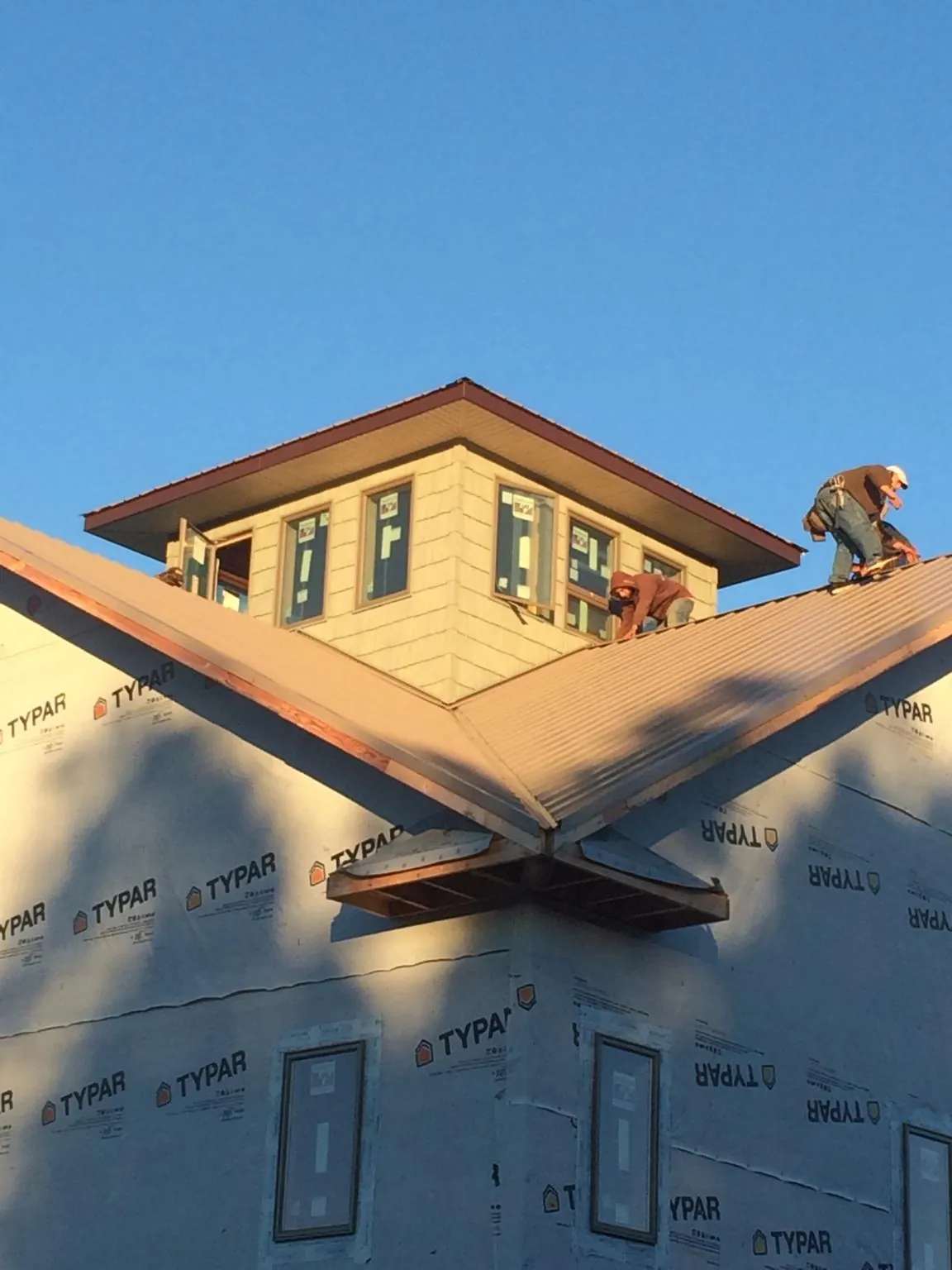 Roofers working around a rooftop cupola on a new metal roof at sunset — Roof Waterproofing in Weymouth by Roofing Brothers
